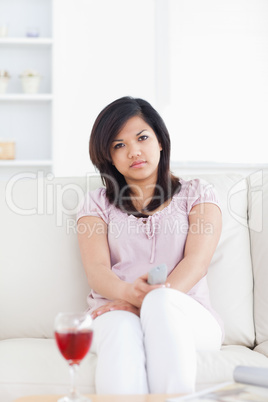 Woman sitting on a couch holding a television remote