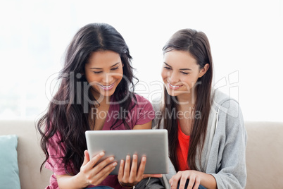 A woman with her friend smiling as they both look at the tablet