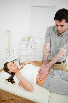 Serious osteopath palpating the stomach of a patient