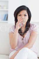 Woman sitting on a couch while drinking a glass of water