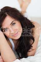 Peaceful brown-haired woman lying on her duvet