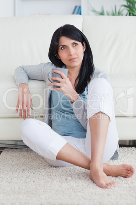 Woman holding a mug while sitting on the floor