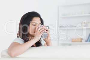 Woman drinking from a mug while holding it with two hands