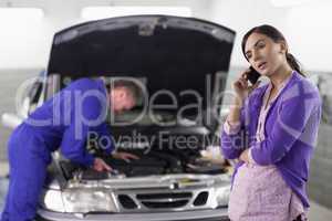 Woman calling next to a mechanic