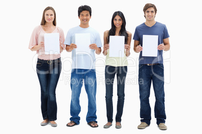 Four people in jeans holding signs