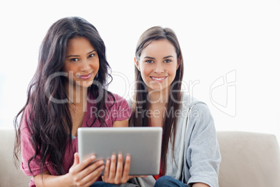 Two ladies with a tablet pc in hand looking at the camera