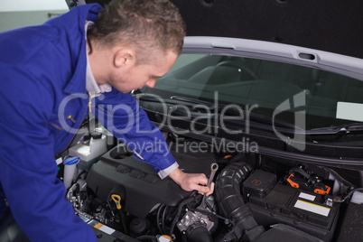 Mechanic repairing the engine with a spanner