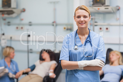 Nurse standing with arms crossed next to patients