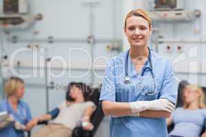 Nurse standing with arms crossed next to patients
