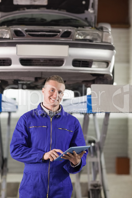 Mechanic touching a tablet computer while looking at camera