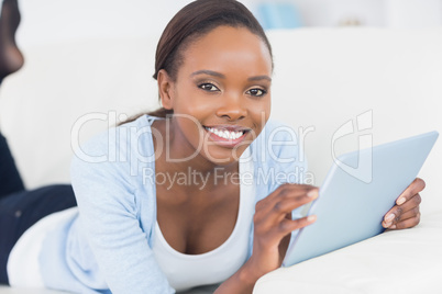 Black woman smiling while holding a tablet computer