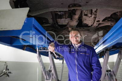 Smiling mechanic leaning on a machine
