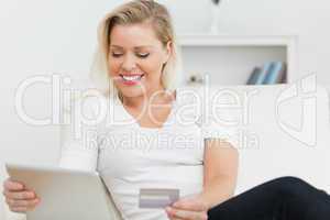 Casual woman sitting on a sofa using a tablet pc