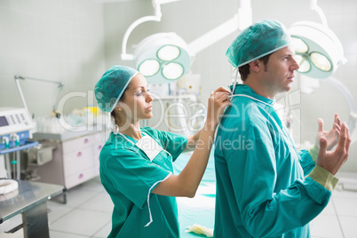 Side view of a nurse helping a surgeon