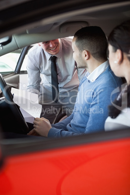 Salesman giving car keys to a couple in a car