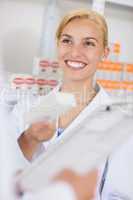 Blonde pharmacist holding a drug box while smiling