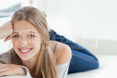 Smiling girl lying on the couch as she looks at the camera