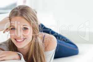 Smiling girl lying on the couch as she looks at the camera