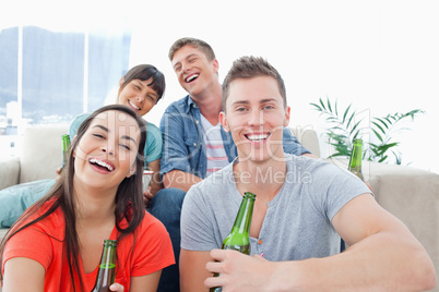 Four people in a living room enjoying beer and having fun togeth