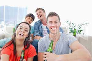 Four people in a living room enjoying beer and having fun togeth