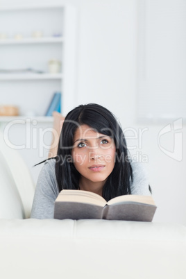 Woman holding a book while relaxing on a sofa