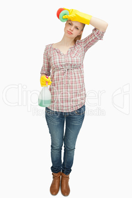 Woman wiping her forehead while holding a spray bottle
