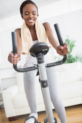 Black woman doing exercise bike while listening music