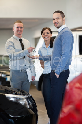 Smiling salesman handing keys to a happy couple