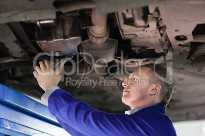 Mechanic repairing the below of a car