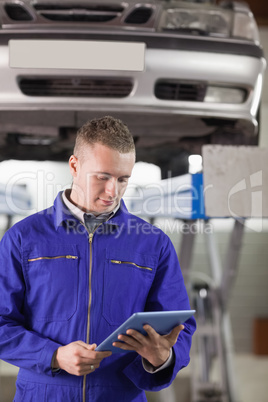 Mechanic looking at a tablet computer while holding it