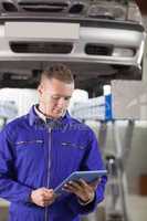 Mechanic looking at a tablet computer while holding it