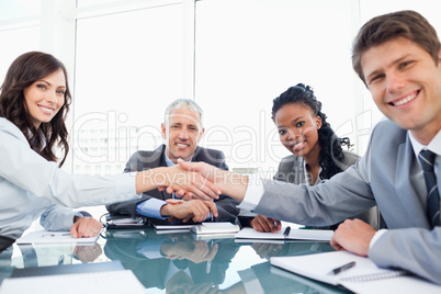 Young executives shaking hands while looking at the camera and s
