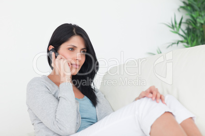 Woman phoning while sitting on a sofa