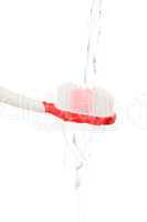 Water flowing on a red toothbrush