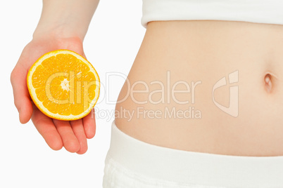 Woman placing an orange near her belly