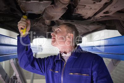 Man looking at the below of a car while repairing