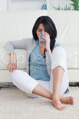 Woman sitting on the floor while drinking from a mug