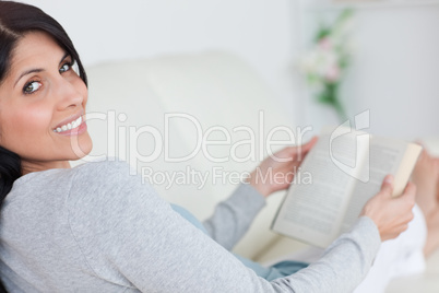 Woman holding a book as she lies on a couch