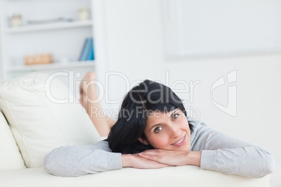 Woman resting on a sofa while resting her head on her arms