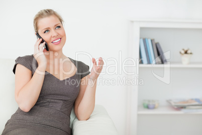 Woman calling while she is sitting on a white sofa