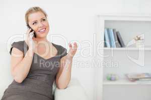 Woman calling while she is sitting on a white sofa