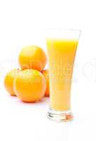 Heap of oranges behind a glass of orange juice