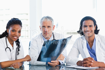 Serious doctor with smiling co-workers looking at an x-ray scan