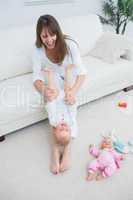 Mother playing with a baby while sitting on a sofa