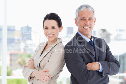 Mature businessman and his secretary standing upright side by si