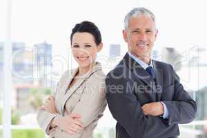 Mature businessman and his secretary standing upright side by si