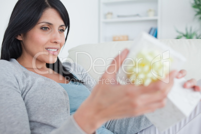 Woman sitting on a couch while opening a gift box