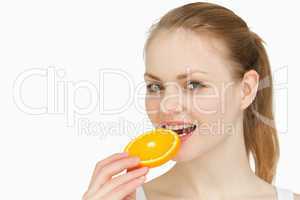Woman placing an orange slice in her mouth