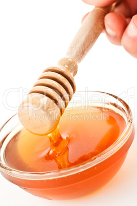 Honey dipper on the top of a bowl dropping honey