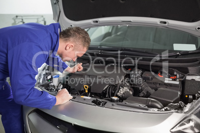 Mechanic looking at an engine of car